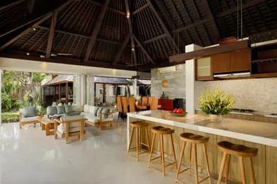 an open kitchen and living room with a bar with stools at Villa Tenang by Nakula in Canggu