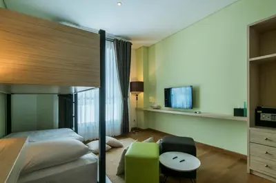 a bedroom with a bunk bed and a green chair at Yan's House Hotel in Kuta