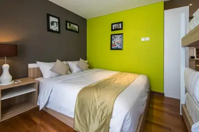 a bedroom with a large bed with a green wall at Yan's House Hotel in Kuta