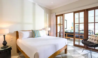 a bedroom with a white bed and a chair at Villa Mandala in Seminyak