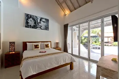 a bedroom with a bed and a large sliding glass door at Grange Villa - Legian in Legian