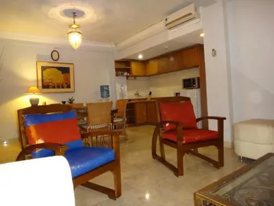 a living room with red and blue chairs and a kitchen at Private Apartments at Jayakarta Resort in Legian