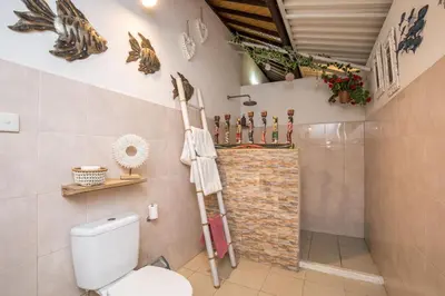 a bathroom with a toilet and a brick wall at Villa Kamboja Younger in Seminyak