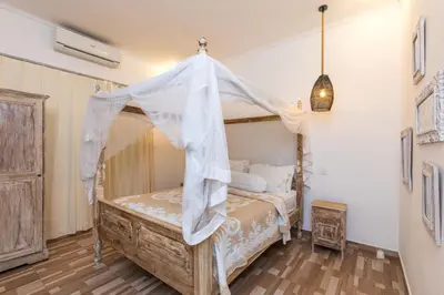 a bedroom with a bed with a canopy at Villa Kamboja Younger in Seminyak