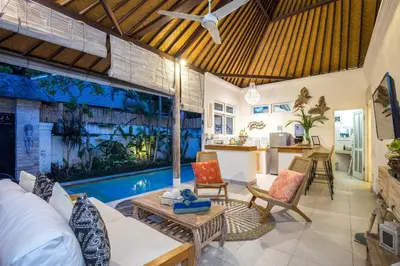 a living room with a couch and a table at Villa Kamboja Younger in Seminyak
