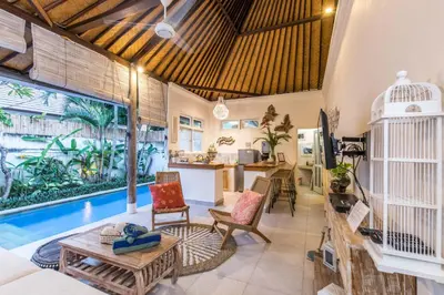 a living room with a pool and a table and chairs at Villa Kamboja Younger in Seminyak