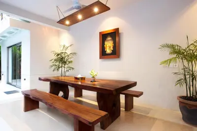 a dining room with a wooden table and benches at Sunset Paradise Villa Jimbaran 8008 in Jimbaran