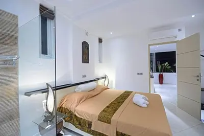 a bedroom with a bed and a glass wall at Flora Apartment Bali in Seminyak