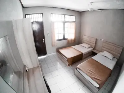 a bedroom with two beds and a window at Palm Garden Kuta in Kuta