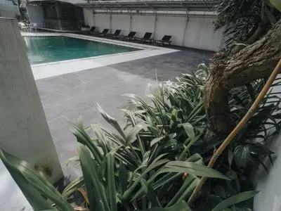 a swimming pool with chairs in a building at Palm Garden Kuta in Kuta