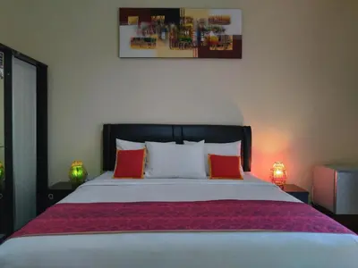 a bedroom with a large bed with red pillows at Beji Ayu Homestay in Seminyak
