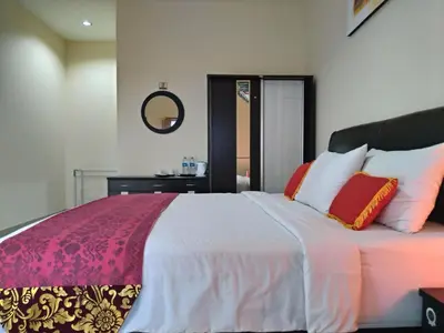a bedroom with a large bed with red and white pillows at Beji Ayu Homestay in Seminyak