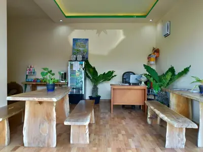 a room with benches and a table and a refrigerator at Beji Ayu Homestay in Seminyak