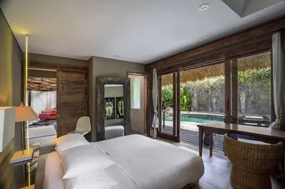 a bedroom with a bed and a table and a pool at Villa Sham in Seminyak
