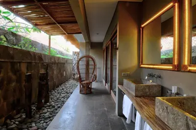 a bathroom with two sinks and a stone wall at Villa Sham in Seminyak