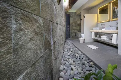 a bathroom with a stone wall and a sink at Villa Sham in Seminyak