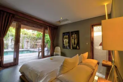 a bedroom with a bed and a sliding glass door at Villa Sham in Seminyak