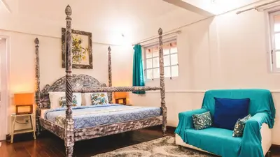 a bedroom with a four poster bed and a blue chair at Villa Alam Biru Gardenia in Seminyak