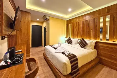 a bedroom with a bed and a table and a television at AB Hotel Kuta in Kuta
