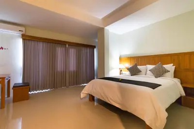a bedroom with a large bed and a large window at AB Hotel Kuta in Kuta