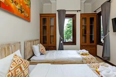 a bedroom with two beds and a window at Villa Tiah in Kuta