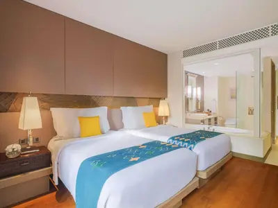 a large bedroom with a large bed and a bathroom at Mövenpick Resort & Spa Jimbaran Bali in Jimbaran