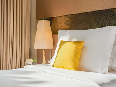 a bedroom with a bed with a yellow pillow at Mövenpick Resort & Spa Jimbaran Bali in Jimbaran