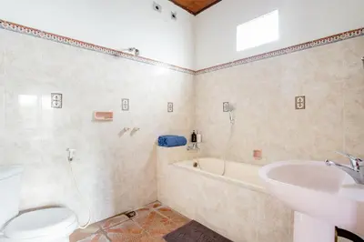 a bathroom with a toilet and a tub and a sink at Rumah Akira Seminyak in Seminyak