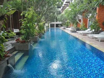 an infinity pool in a hotel with blue water and trees at Jambuluwuk Oceano Seminyak Hotel in Seminyak