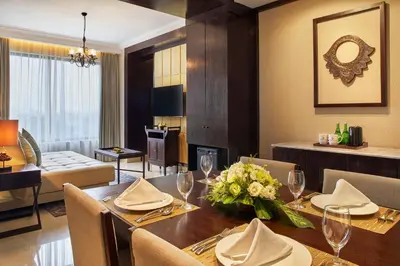 a dining room with a table and a living room at Jambuluwuk Oceano Seminyak Hotel in Seminyak