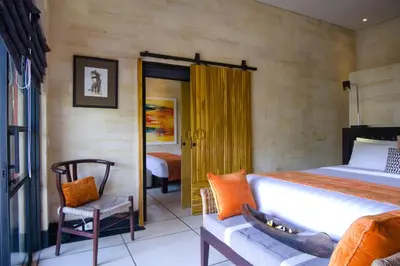 a bedroom with a large bed and a chair at Amanputri Villa in Seminyak