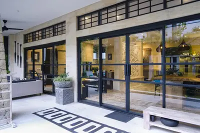 a house with glass doors and a bench at Amanputri Villa in Seminyak