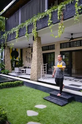 a man standing on the grass in front of a house at Amanputri Villa in Seminyak