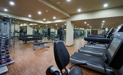 a gym with a row of treadmills and machines at The Sintesa Residence Jimbaran in Jimbaran