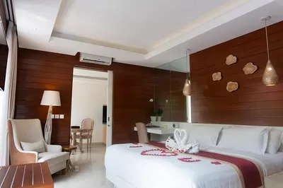 a bedroom with a large white bed and wooden walls at Sithala Villa Seminyak in Seminyak