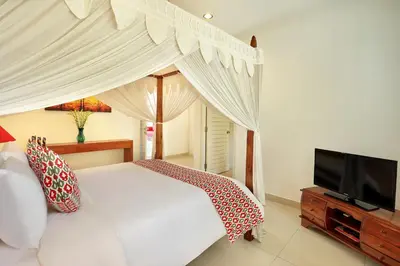 a bedroom with a white bed and a flat screen tv at Villa Lamac in Legian