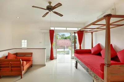 a bedroom with a red bed and a ceiling fan at Villa Lamac in Legian