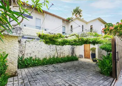a white house with a fence and a brick driveway at Bali Villa Beachfront Luxe Rooftop Sunsets in Canggu