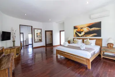 a bedroom with a large bed and a large painting on the wall at Villa Aveli Seminyak by Best Deals Asia Hospitality in Seminyak