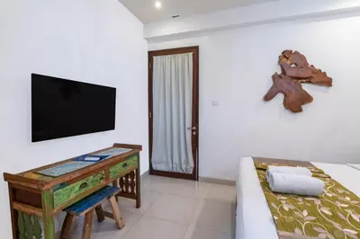 a room with a tv and a bed and a table at Villa Aveli Seminyak by Best Deals Asia Hospitality in Seminyak