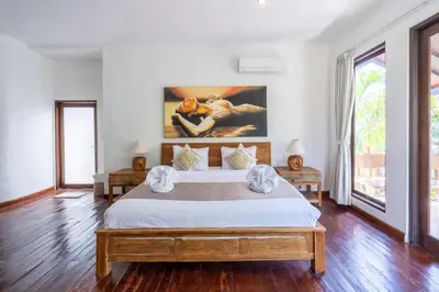 a bedroom with a large bed and a painting on the wall at Villa Aveli Seminyak by Best Deals Asia Hospitality in Seminyak