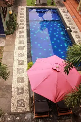 a pink umbrella sitting next to a swimming pool at Nuka Beach Inn in Kuta