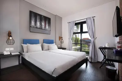 a bedroom with a large white bed and a window at The Aswana Seminyak in Seminyak