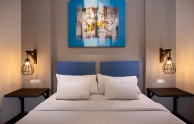 a bedroom with a bed with two lamps and a painting at The Aswana Seminyak in Seminyak