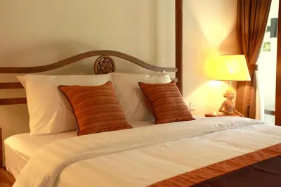 a bedroom with a bed with white sheets and orange pillows at Adys Inn in Legian
