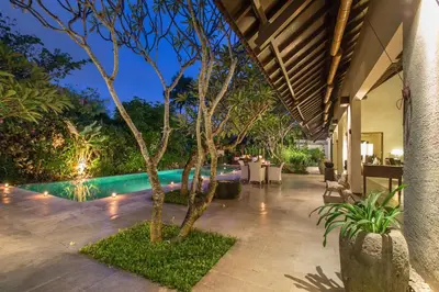 an outdoor patio with a swimming pool and trees at Villa Roku by Nagisa Bali in Seminyak