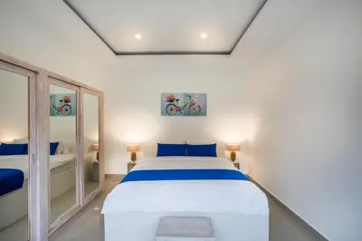a bedroom with a large white bed with blue pillows at Holyfat Villa in Seminyak