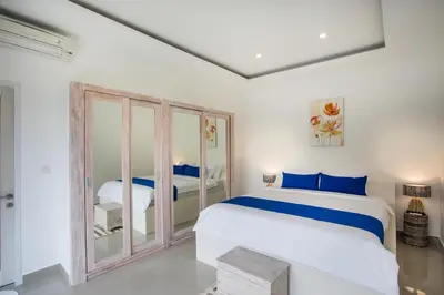a white bedroom with a bed and two beds at Holyfat Villa in Seminyak