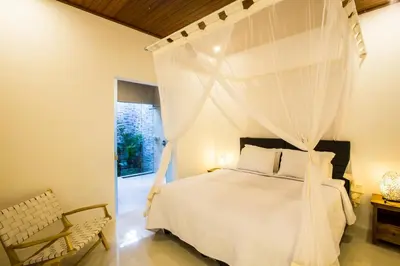 a bedroom with a white bed with a canopy at Villa Kamboja Deluxe in Seminyak