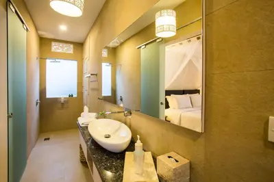 a bathroom with a sink and a mirror and a bed at Villa Kamboja Deluxe in Seminyak